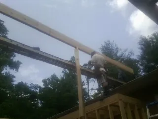 Carpenter setting a ridge beam over a new addition frame — Ice Dam Removal by Roofing Brothers in Catoosa