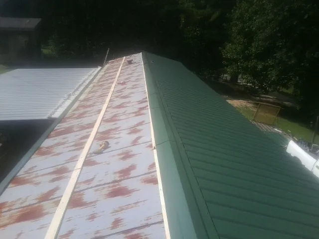 Old rusted panels beside newly installed green metal roofing — Wind Damage Roof Repair by Roofing Brothers in Catoosa