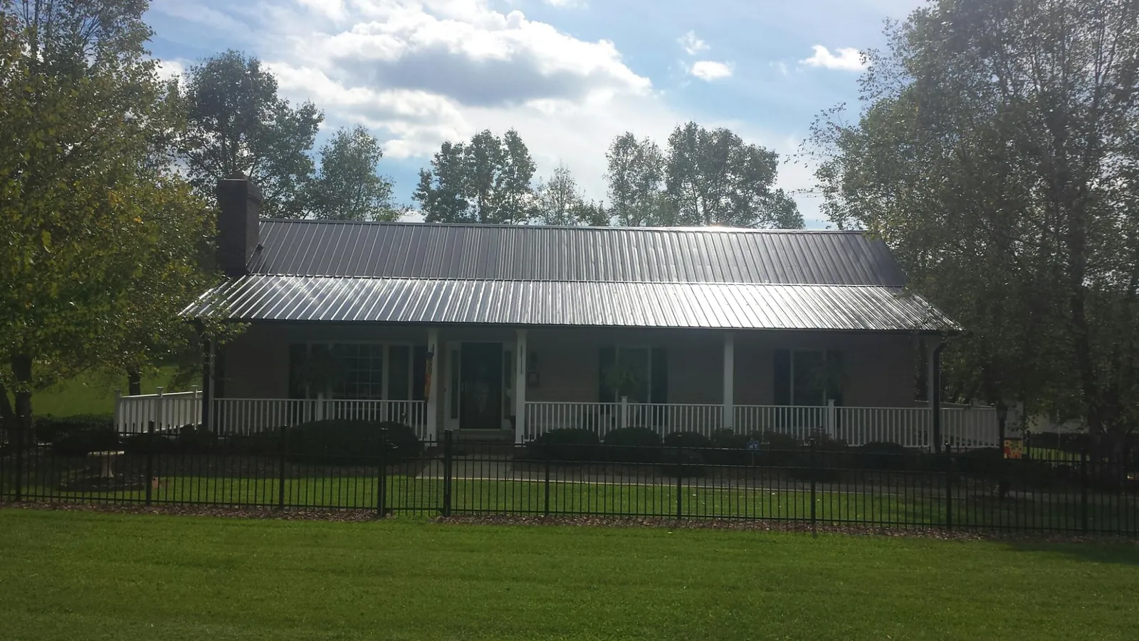 Gray metal roof on a brick ranch with a full width front porch — Gutter Guard Installation work by our crew in Catoosa