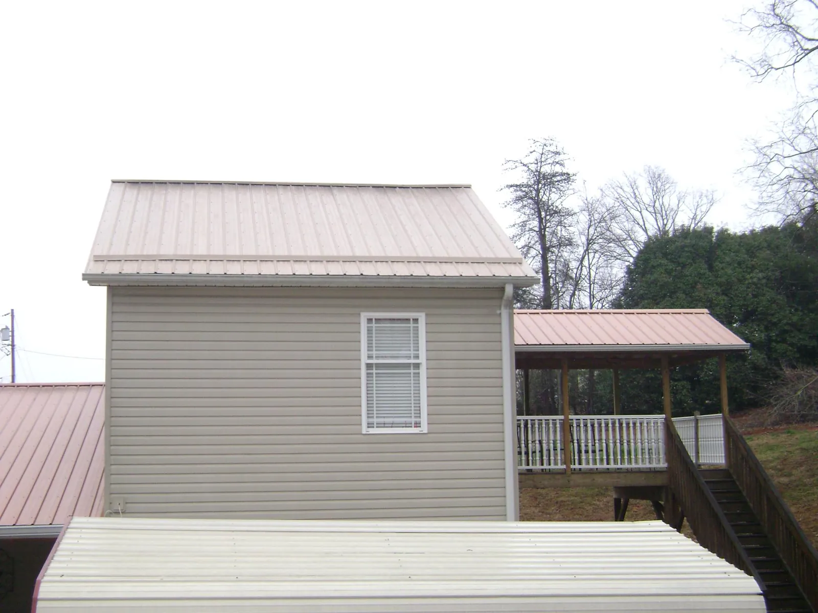 Tan metal roofs on a two story addition and attached porch, from a Roof Replacement job in Catoosa
